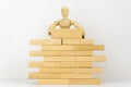 Wooden man builds wall of wooden blocks. concept of creation, construction, business development