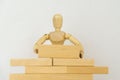 Wooden man builds wall of wooden blocks. concept of creation, construction, business development