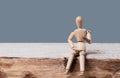 Wooden man dummy sits and speaks on a gray background. Place for text Royalty Free Stock Photo