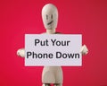 A wooden man holds a card with phrase Put Your Phone Down Royalty Free Stock Photo