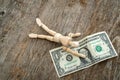 Wooden man reaches for the last dollar bill