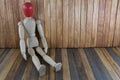 Wooden man with a red head sitting on wooden background Royalty Free Stock Photo