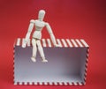 Wooden man sitting on empty gift box on red background Royalty Free Stock Photo