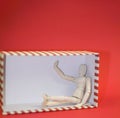 Wooden man sitting in empty gift box on red background Royalty Free Stock Photo