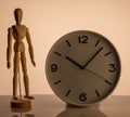 Wooden man toy and clock on beige background Royalty Free Stock Photo