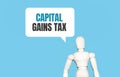 The wooden man and white cloud with text CAPITAL GAINS TAX. The content of the lettering has implications for business concept and Royalty Free Stock Photo