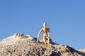 Wooden mannequin, figurine of a man sitting on a bare rock against the sky. The concept of loneliness. Royalty Free Stock Photo