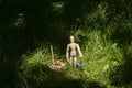 Wooden mannequin in green grass with miniature bucket and shovel