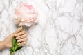 Wooden mannequin hand with piony flower on marble background