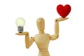 Wooden mannequin holding light bulb and heart on hands on white background - Concept of love priority over brain in life Royalty Free Stock Photo