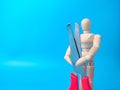 A wooden mannequin holding red scissors on a blue background with copy space Royalty Free Stock Photo