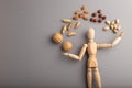 Wooden mannequin juggling nuts on gray pastel background. copy space