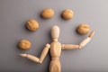Wooden mannequin juggling walnuts on gray pastel background. close up