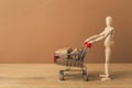 Wooden mannequin with miniature shopping cart Royalty Free Stock Photo