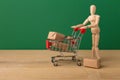 Wooden mannequin with miniature shopping cart Royalty Free Stock Photo