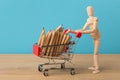 Wooden mannequin with miniature shopping cart Royalty Free Stock Photo