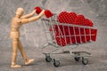 Wooden mannequin pushing shopping cart full of hearts Royalty Free Stock Photo