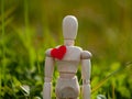 Wooden mannequin with a red heart on his chest. Concept of romanticism and love Royalty Free Stock Photo