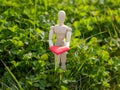 Wooden mannequin with a red heart on his hands in the grass. Concept of romanticism and love Royalty Free Stock Photo