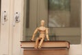 A wooden mannequin sits on a stack of books against the background of an old window. Royalty Free Stock Photo