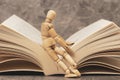 Wooden mannequin sitting on the open book Royalty Free Stock Photo