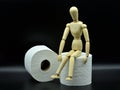 Wooden mannequin sitting on a roll of toilet paper