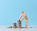 Wooden mannequin and a stack of coins on a blue background Royalty Free Stock Photo