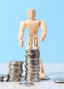 Wooden mannequin and a stack of coins on a blue background. Business indicators growth concept, income growth Royalty Free Stock Photo