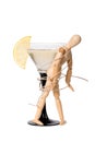 Wooden mannikin strapped to the glass of vermouth. Concept of drunkenness, alcohol abuse