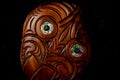 Wooden Maori Hei Tiki hand carved with paua shell eyes. New Zealand taonga. Closeup dark background. Royalty Free Stock Photo