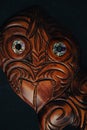 Wooden Maori Hei Tiki hand carved with paua shell eyes. New Zealand taonga. Closeup dark background. Royalty Free Stock Photo