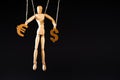 Wooden marionette on strings holding currency