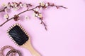 Wooden massage comb, spirals for hair and flowering apricot branch on pink background. beauty girl female concept Royalty Free Stock Photo