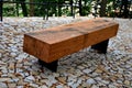 wooden massive park bench shape block with metal legs on granite natural cobblestone irregular brown gray pavement on pedestrian