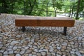 wooden massive park bench shape block with metal legs on granite natural cobblestone irregular brown gray pavement on pedestrian