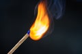 Wooden match stick with blue head ignited and burning bright big fire on black Royalty Free Stock Photo