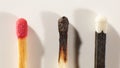 Wooden matche with red head, black wooden matche with white head and burnt match on a light gray background close-up