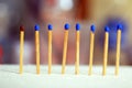 Wooden matches standing on bright colorful background. With one brown match and the other matches in blue colors.