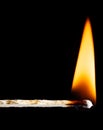Wooden matchstick flaming with an orange flame against a black Royalty Free Stock Photo