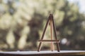 Wooden mini easel stands on windowsill in front of nature, art work and inspiration concept