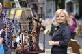 Wooden mini sculptures put up for sale during street fair, woman artist standing near to sell them