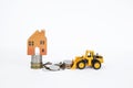 Wooden miniature house on coins stack with front loader truck moving coins Royalty Free Stock Photo