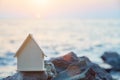 Wooden miniature of house on rock. Sunset over ocean. Housing rental near sea concept. Summer holiday idea, copy space Royalty Free Stock Photo