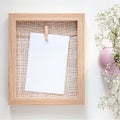 A wooden mockup frame with a white card and a pink vase