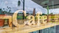 Wooden mockup signboard for cafe behind a large glass window that reflects the view outside the coffee shop for background