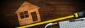 Wooden Model House on a Wooden Desk with a Tape Measure Royalty Free Stock Photo