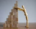 Wooden model of human put wooden blocks on the stack of wooden blocks. Concept of building success foundation Royalty Free Stock Photo