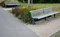 Wooden modern park bench with a metal relief structure on one leg stands in the park in rest areas and on paths made of a small Royalty Free Stock Photo