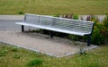 Wooden modern park bench with a metal relief structure on one leg stands in the park in rest areas and on paths made of a small Royalty Free Stock Photo