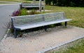 wooden modern park bench with a metal relief structure on one leg stands in the park in rest areas and on paths made of a small Royalty Free Stock Photo